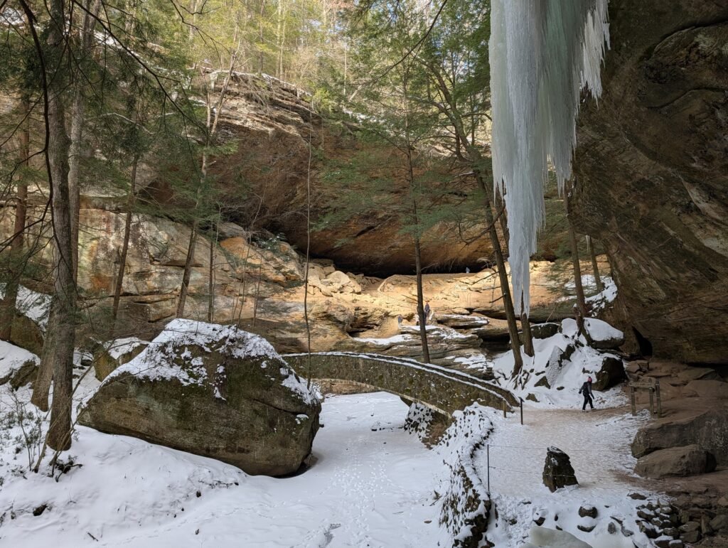 A bridge moves from one side of a gorge to another, while snow covers the ground and icicles hang from rock